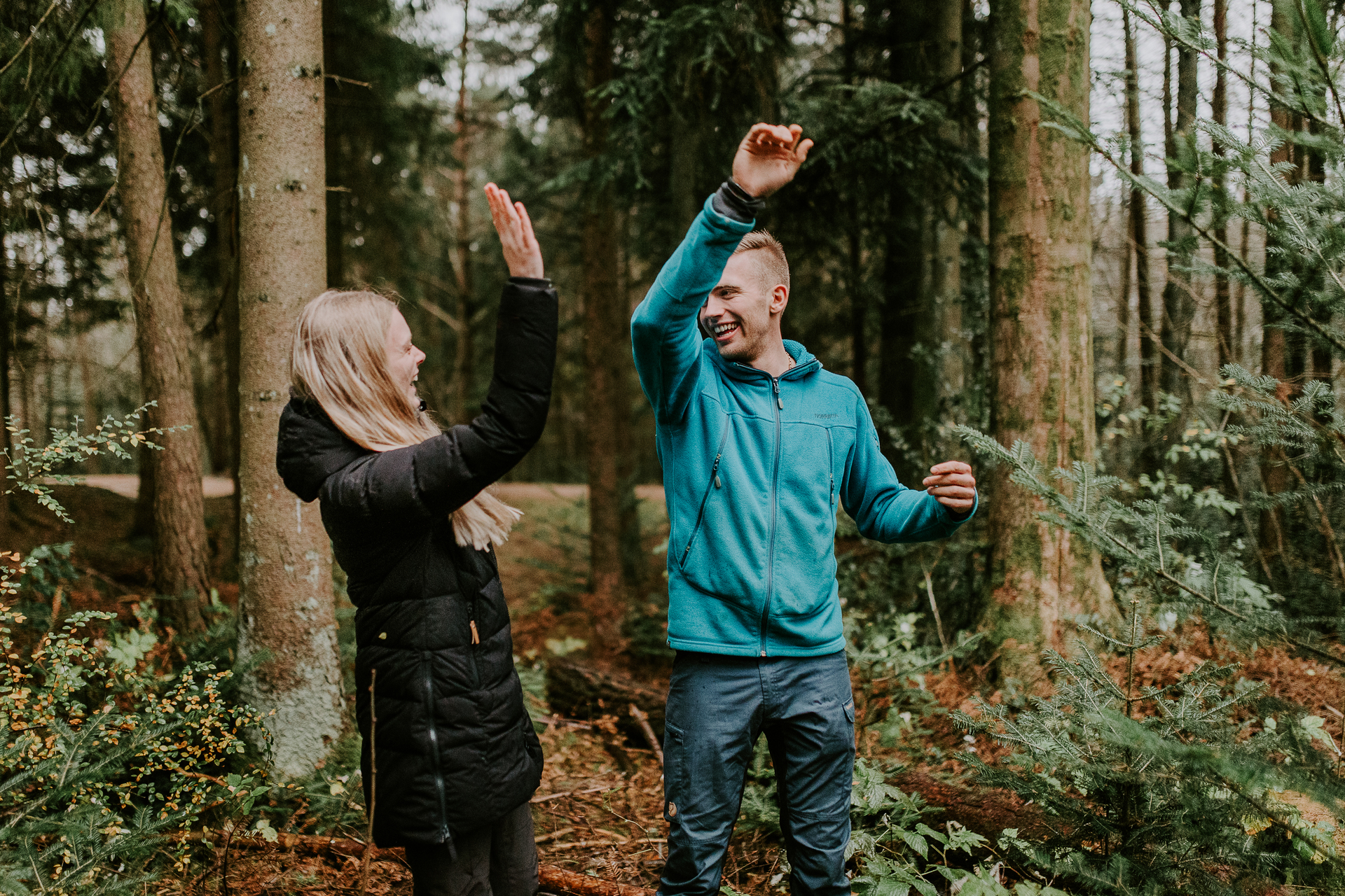 En mann og en kvinne gir hverandre en high five i skogen. 