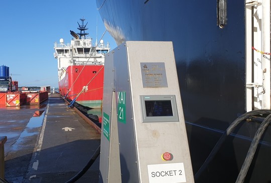 Offshorefartøy er koblet til landstrømanlegg på kaien. Et rødt og hvitt offshorefartøy sees i bakgrunnen. 