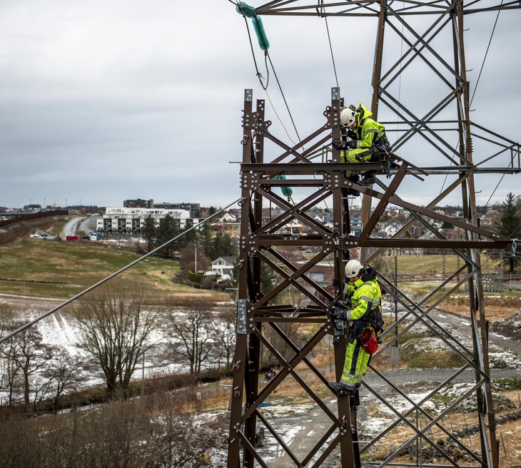 To energimontører er i ferd med å sette opp en mast i Sandnes