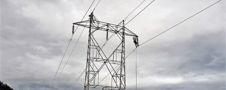 To montører arbeider i toppen av en strømmast