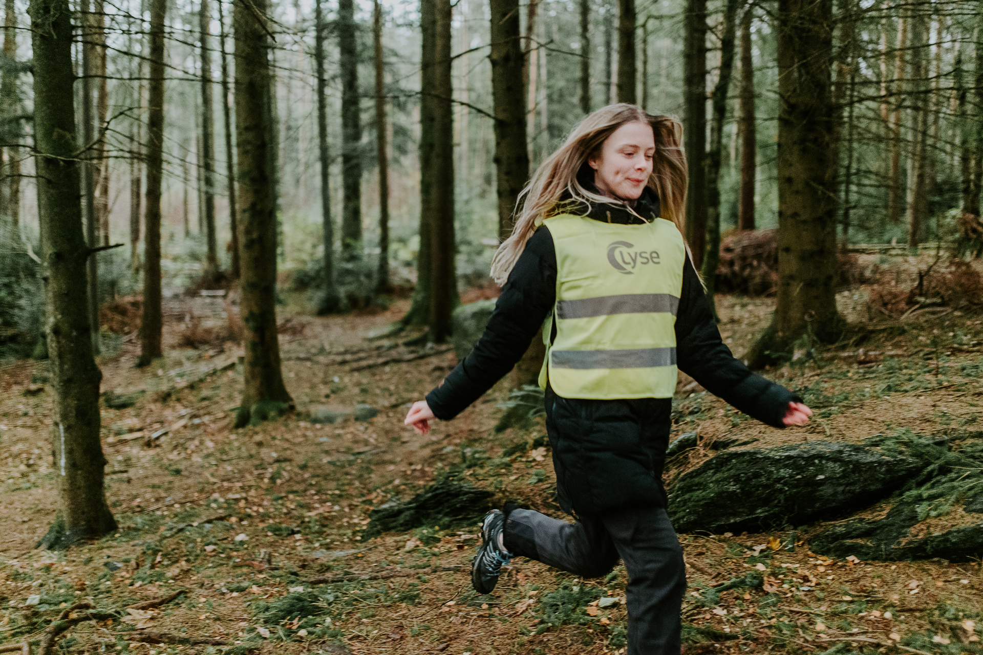 Dame i refleksvest fra Lyse løper i skogen.